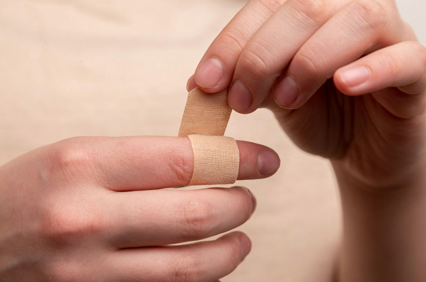 Person putting a bandage on their finger; image by Diana Polekhina, via Unsplash.com.