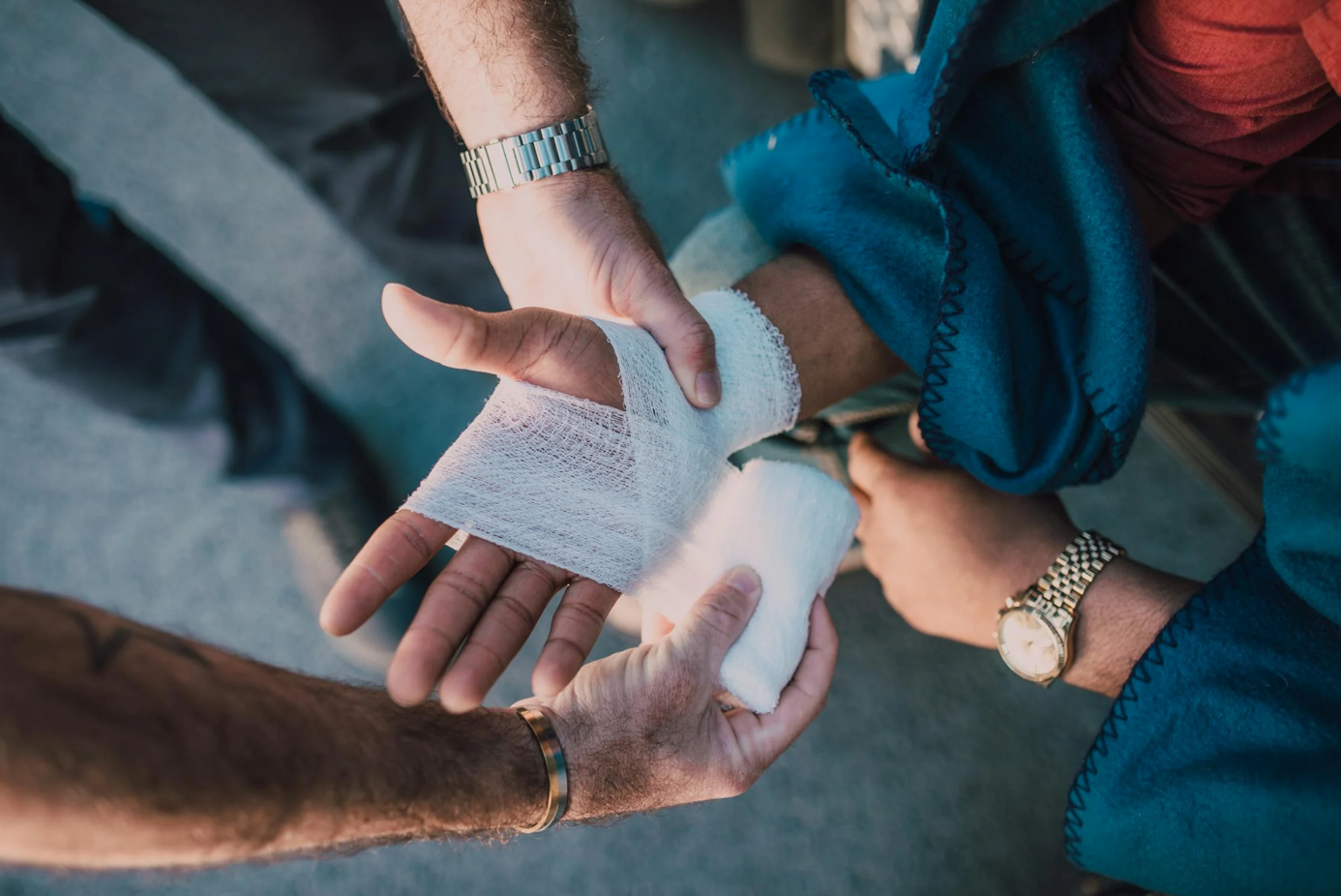 Man applying bandage to someone's hand; image by RDNE Stock project, via Pexels.com.
