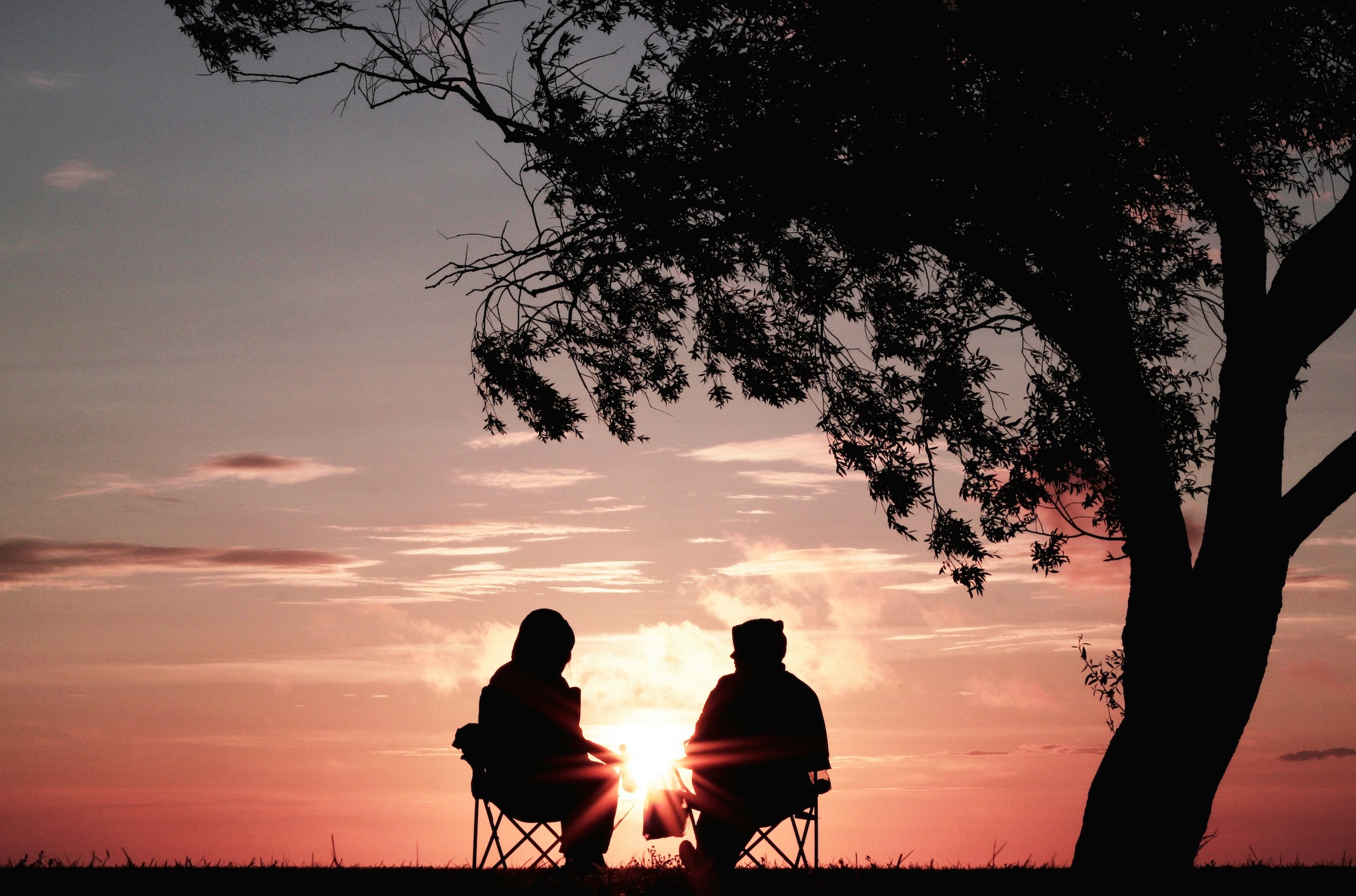 Older couple watching sunset; image by Harli Marten, via Unsplash.com.