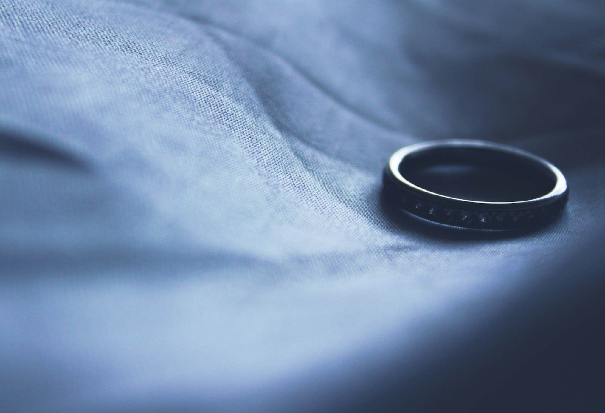 Wedding ring on blue cloth background; image by Siora Photography, via Unsplash.com.