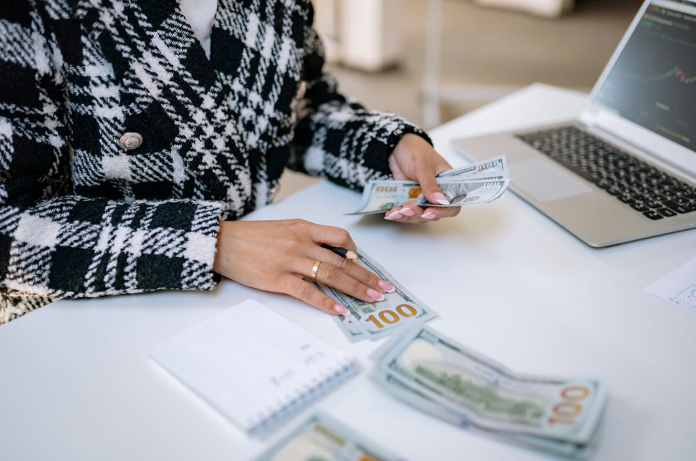 Woman counting money at desk; image by Yan Krukau, via Pexels.com.