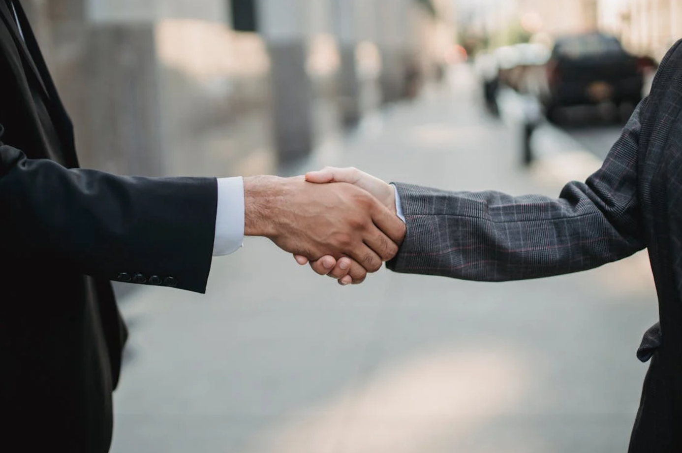 Two men in suits shaking hands; image by Ketut Subiyanto, via Pexels.com.