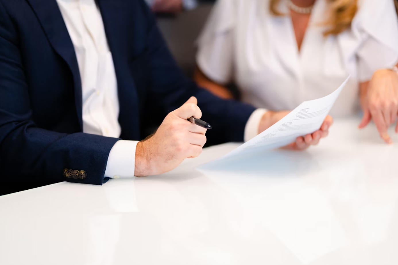 Man and woman at white table reviewing paperwork; image by Carrie Allen www.carrieallen.com, via Unsplash.com.