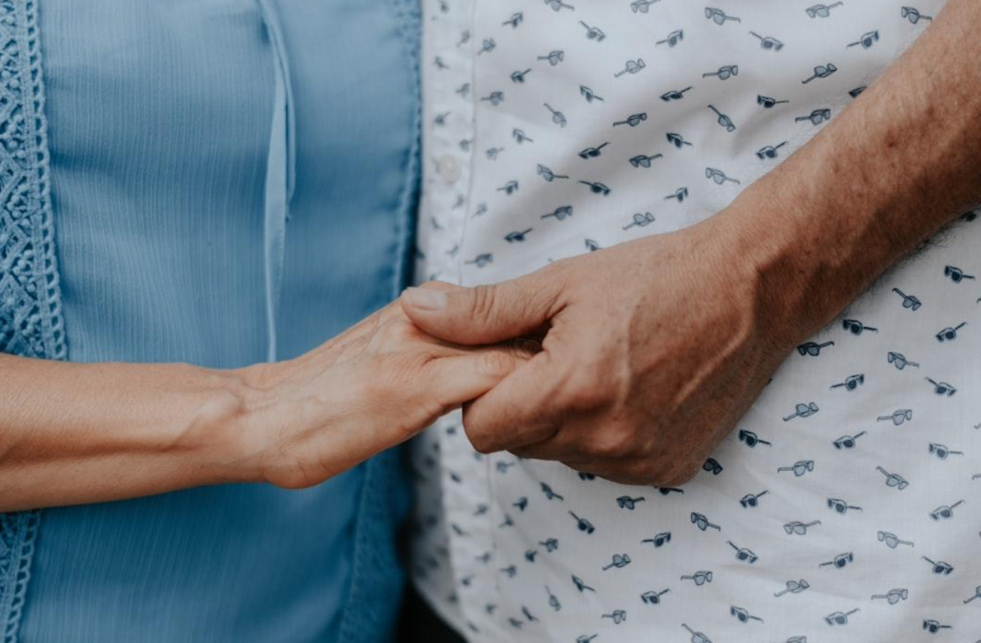 Woman in blue shirt holding hands with man in white shirt with sunglasses print; image by Nani Chavez, via Unsplash.com.