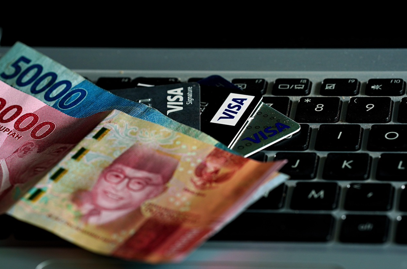 Cash and credit cards on a keyboard; image by ignartonosbg, via Pixabay.com.