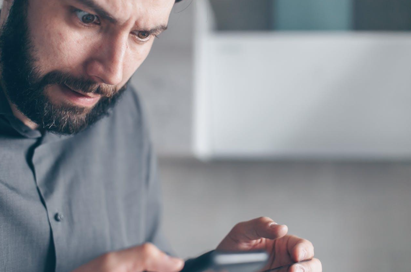 Man in gray shirt looking at smartphone. Image by Mikhail Nilov, via Pexels.com.