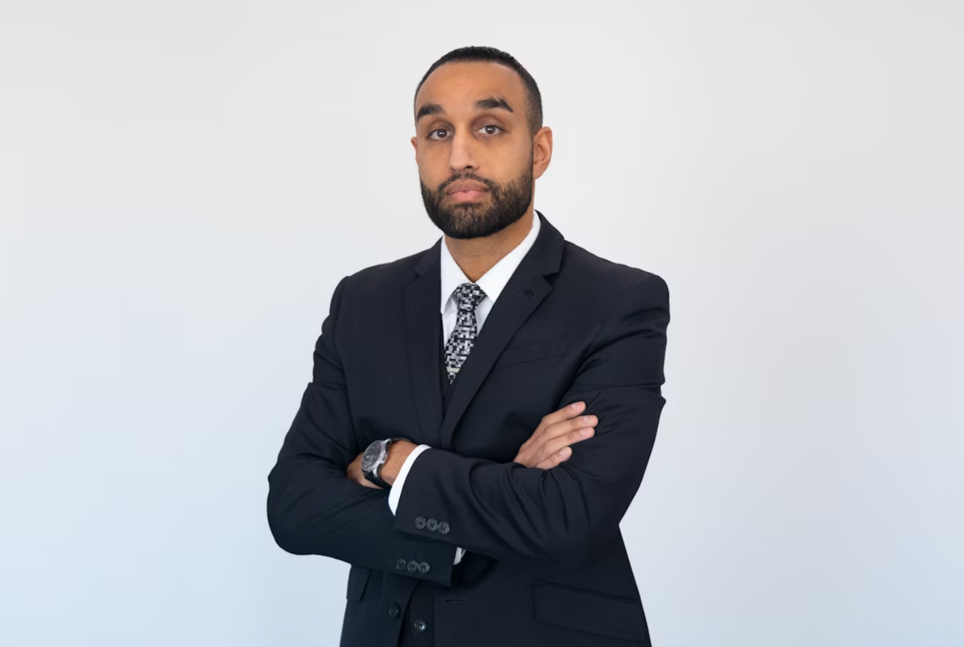 Tall male lawyer standing confidently in expensive suit with arms crossed; image by Nussbaum Law, via Unsplash.com.