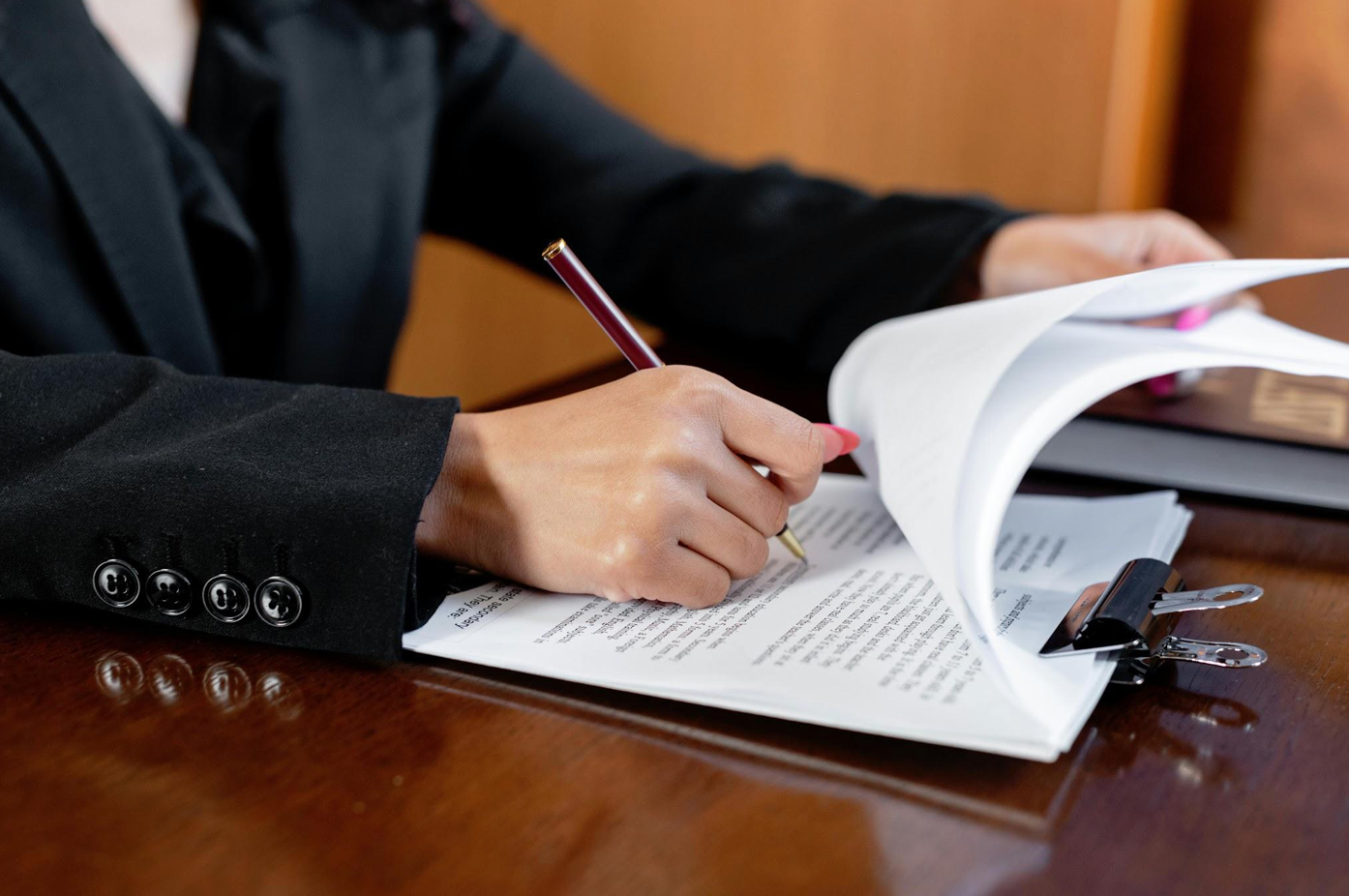 Woman writing on document; image by Mikhail Nilov, via Pexels.com.