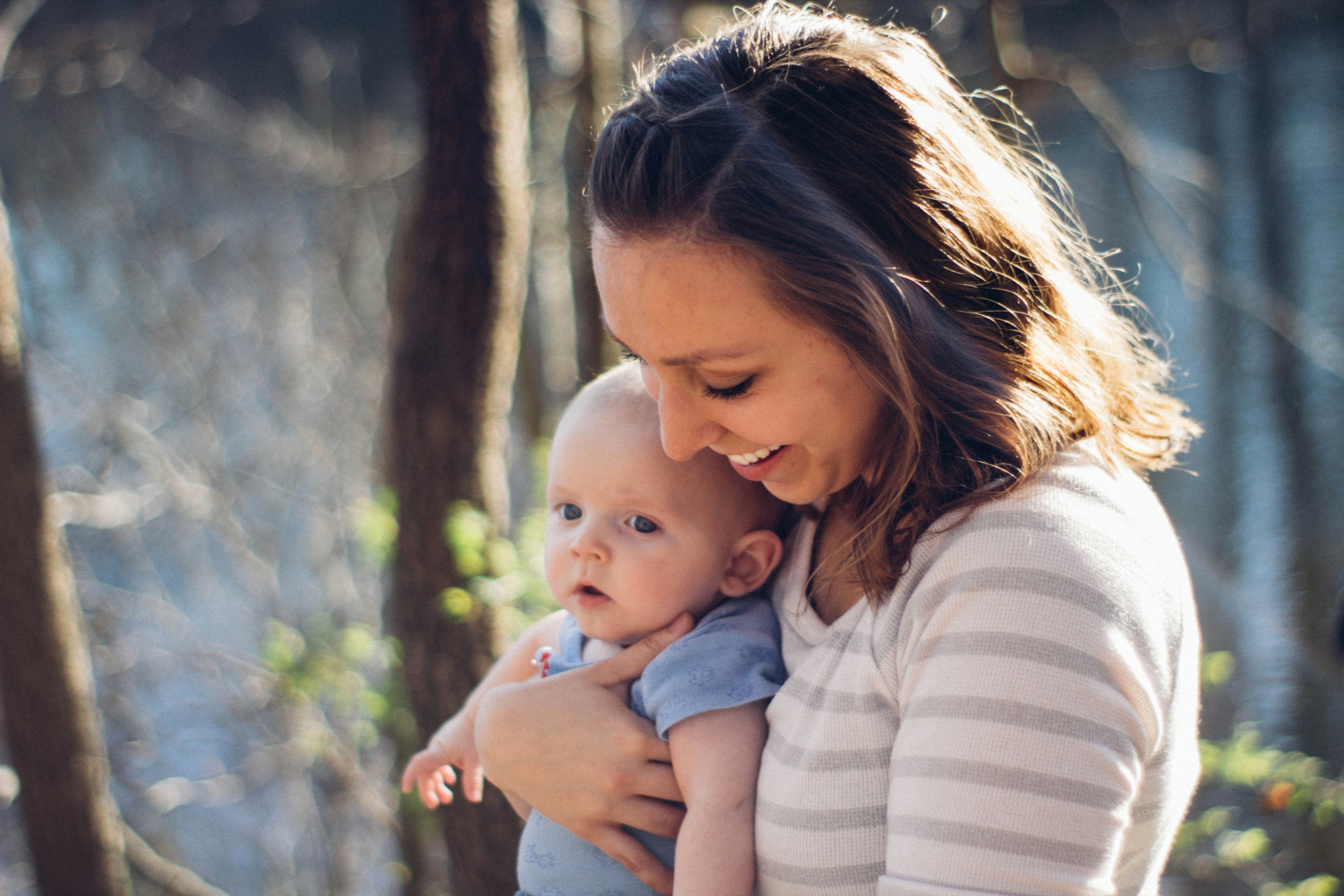 Woman carrying baby near trees; image by Joshua Rodriguez, via Unsplash.com.