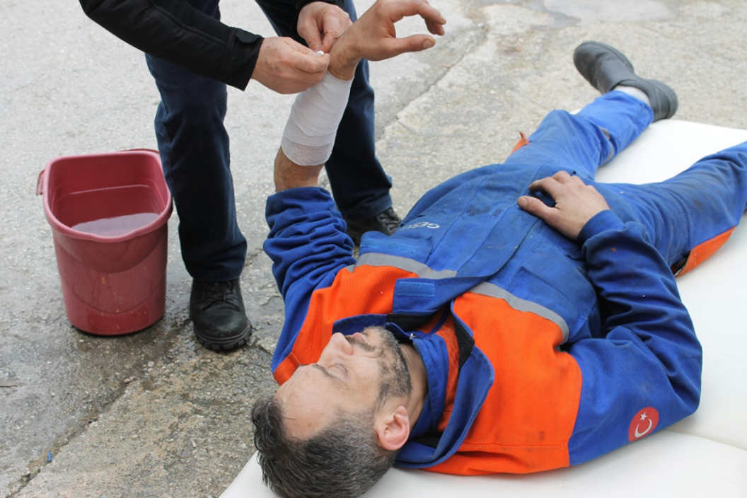 Injured man lying on the ground receiving first aid; image by Elif, via Pexels.com.