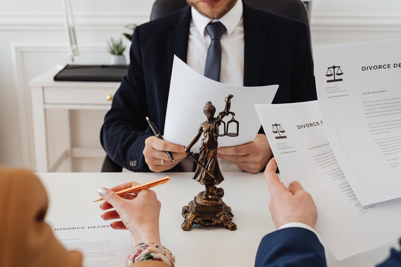 Lawyer and clients reviewing divorce papers; image by Karola G, via Pexels.com.