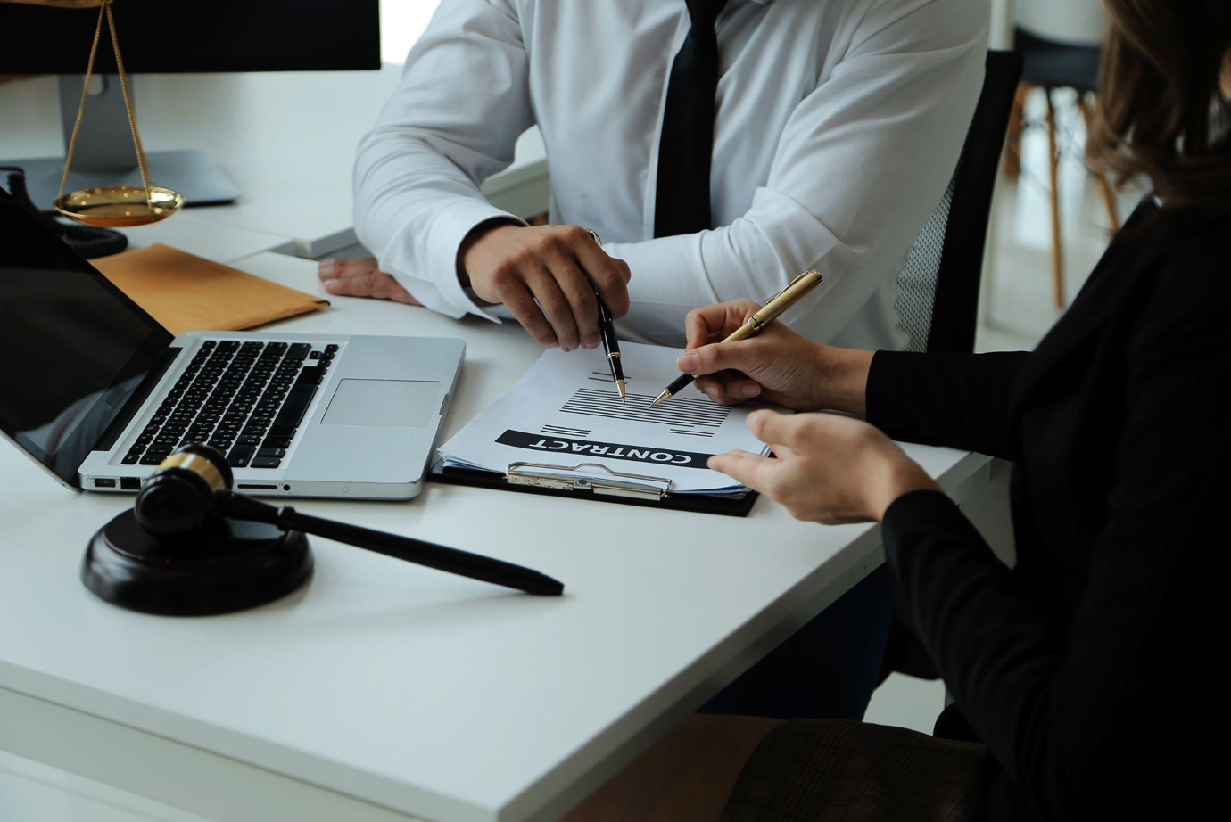 Man and woman meeting at desk with gavel, laptop, and paperwork; image by armmypicca, via Freepik.com.