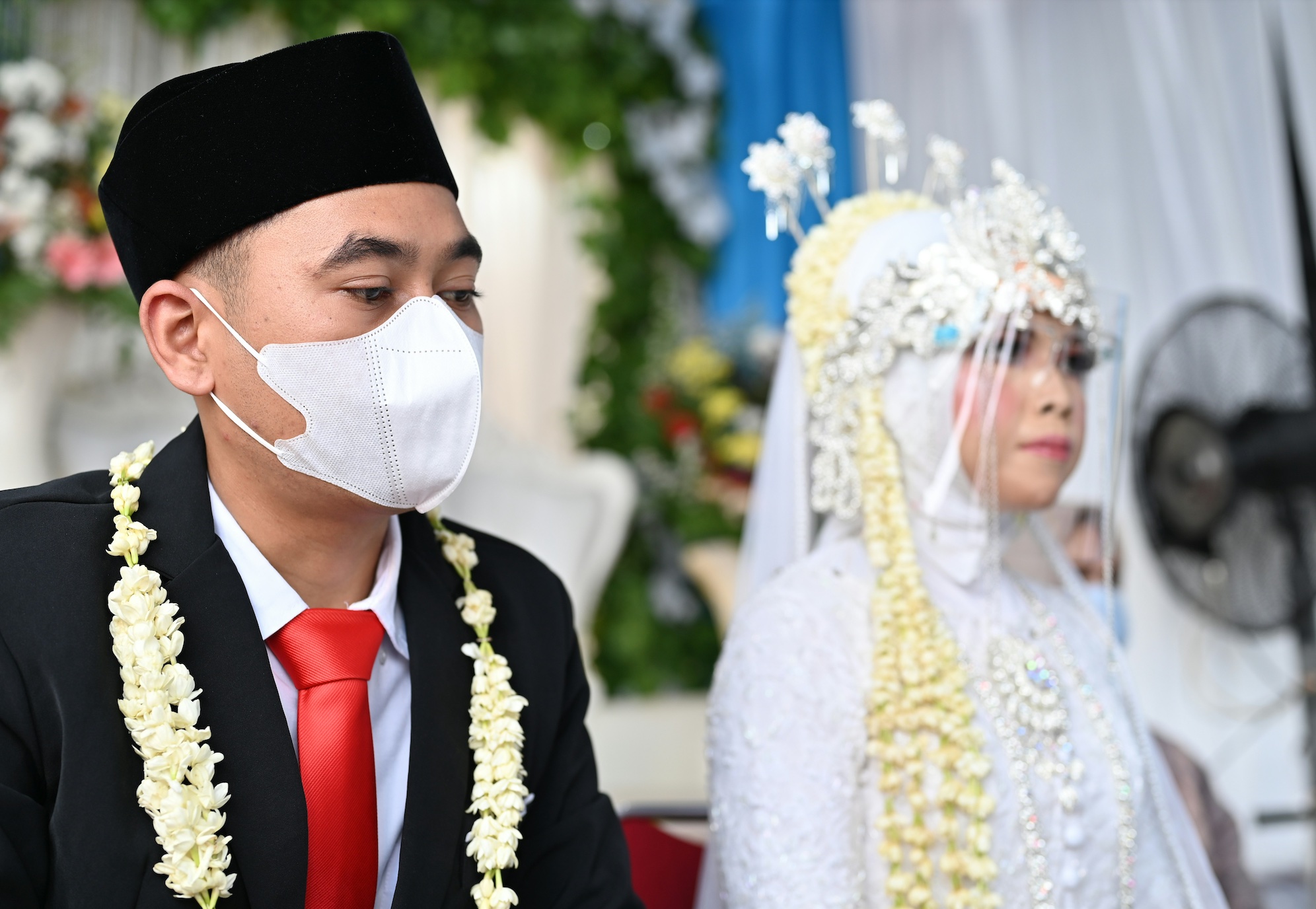 Indonesian bride and groom with face mask and face shield; image by ochimax studio, via Unsplash.com.
