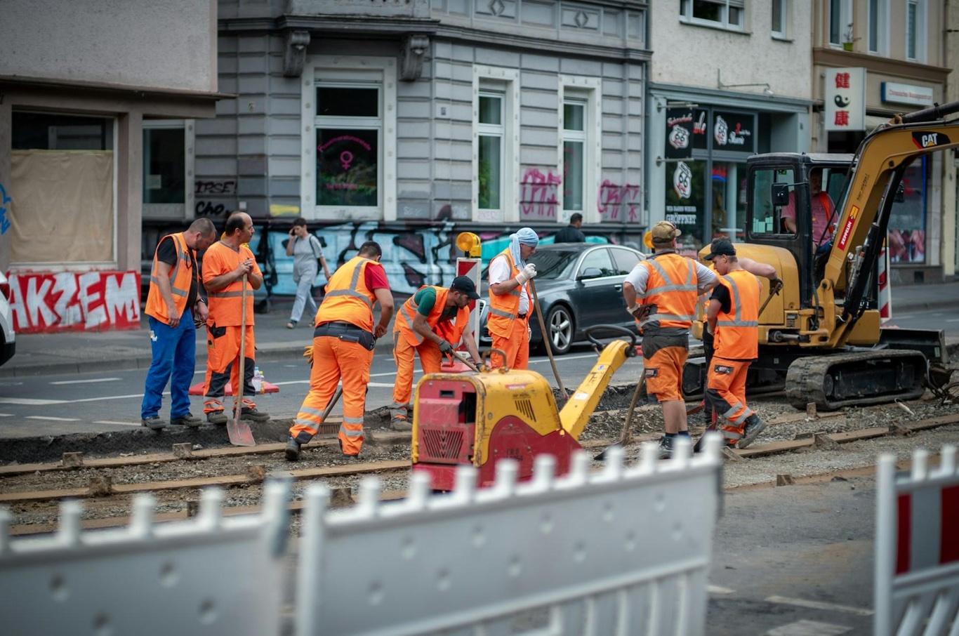 Construction workers in hi-viz orange; image by Mika Baumeister, via Unsplash.com.