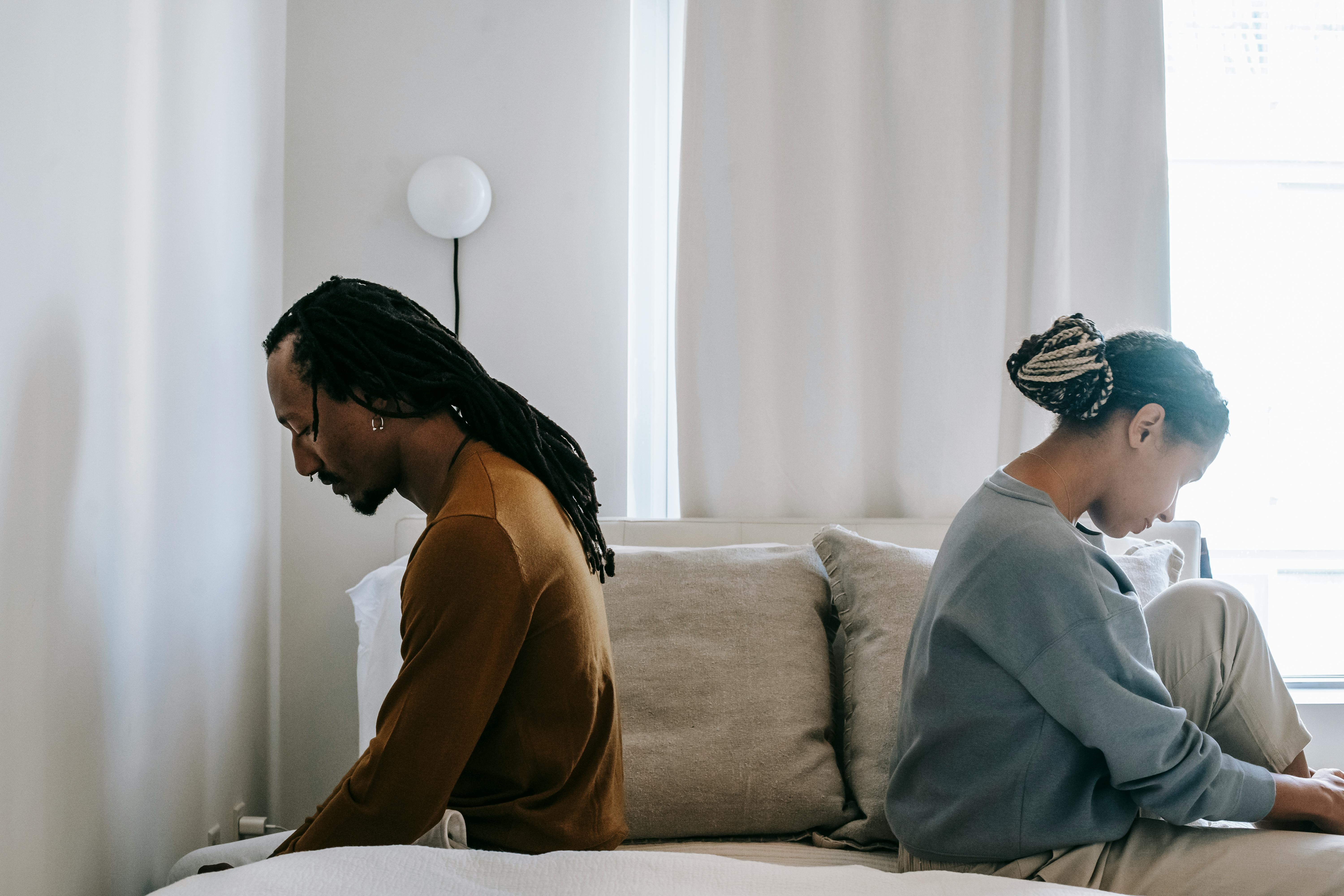 Concerned black couple sitting on bed in misunderstanding; image by Alex Green, via Pexels.com.