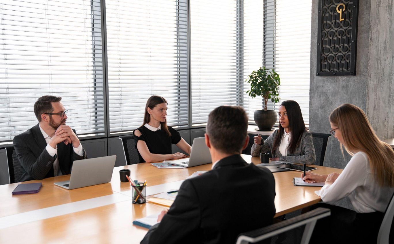 People sitting around conference table; image by Freepik, via Freepik.com.