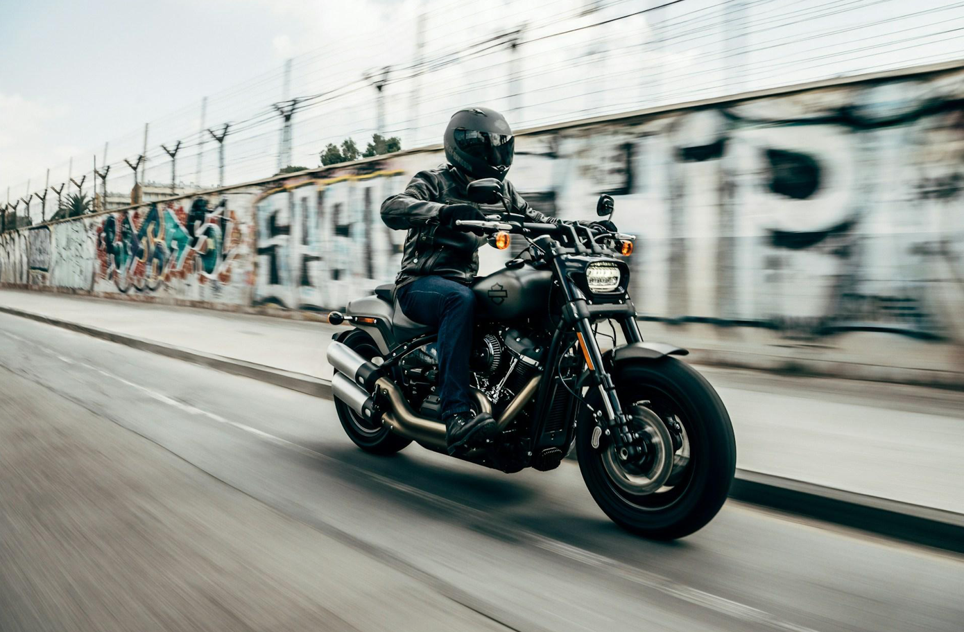 Person riding motorcycle on concrete road; image by Harley-Davidson, via Unsplash.com.