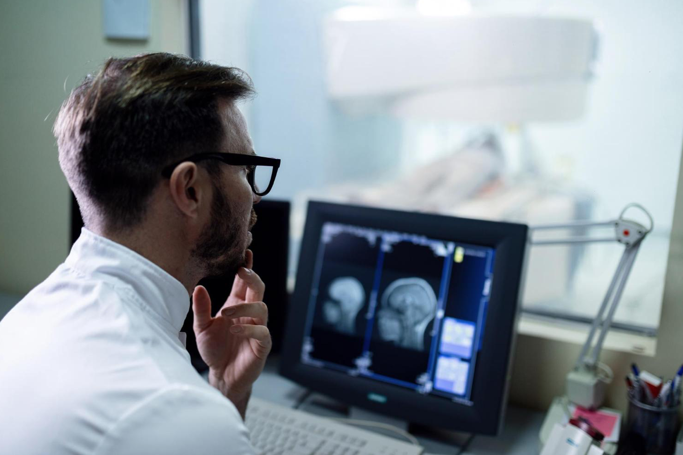 Doctor examining MRI scan of patient's brain; image by Drazen Zigic, via Freepik.com.