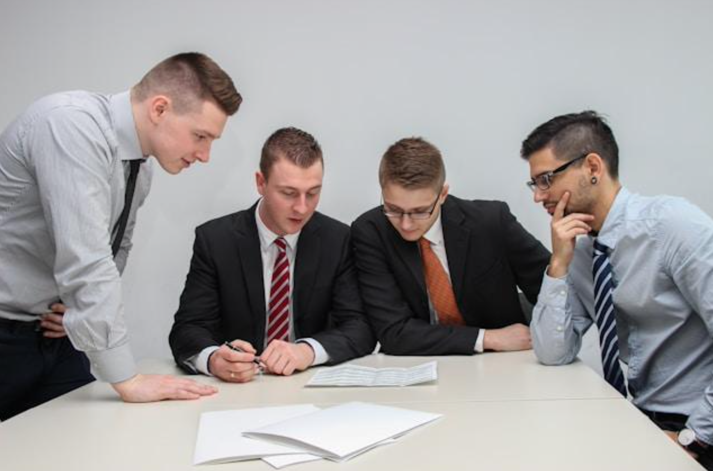 Four men looking at paper on table; image by Sebastian Herrmann, via Unsplash.com.