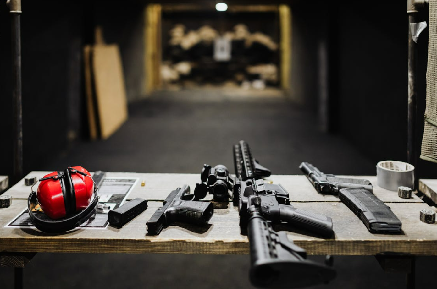 Guns and hearing protection on the table at gun range; image by www.kaboompics.com, via Pexels.com.