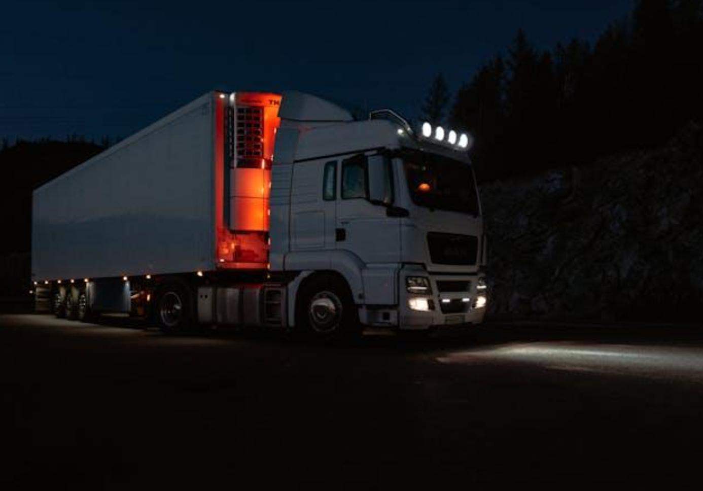 White truck at night with lights on; image by Sergei Skrynnik, via Pexels.com.