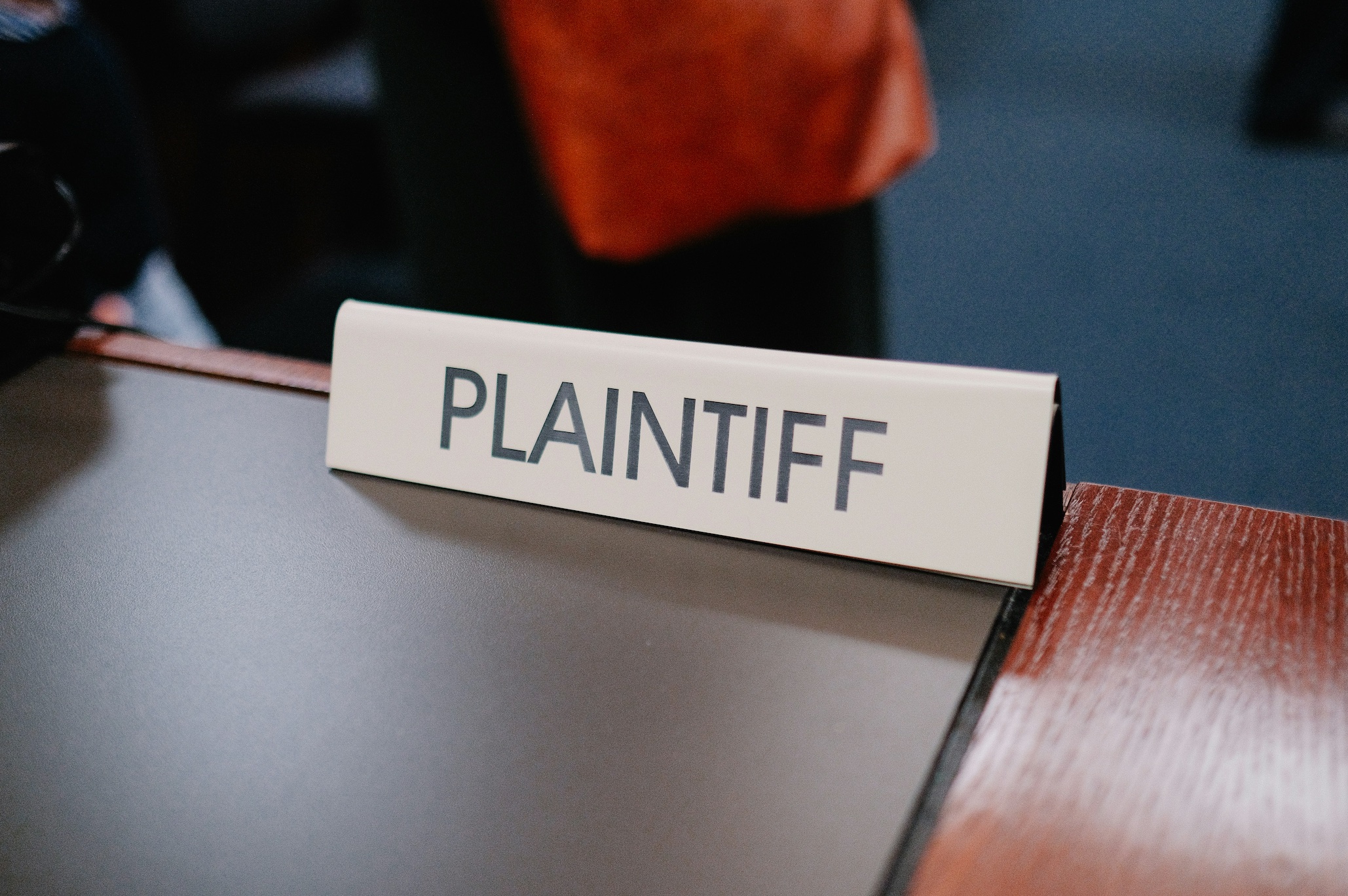 Close up of sign reading Plaintiff on table; image by Wesley Tingey, via Unsplash.com.
