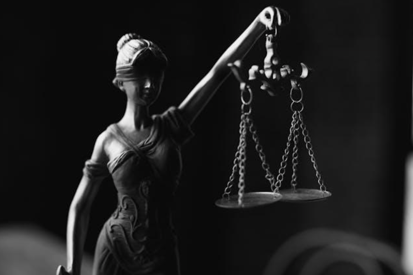 Greyscale image of Lady Justice statue; image by KATRIN BOLOVTSOVA, via Pexels.com.