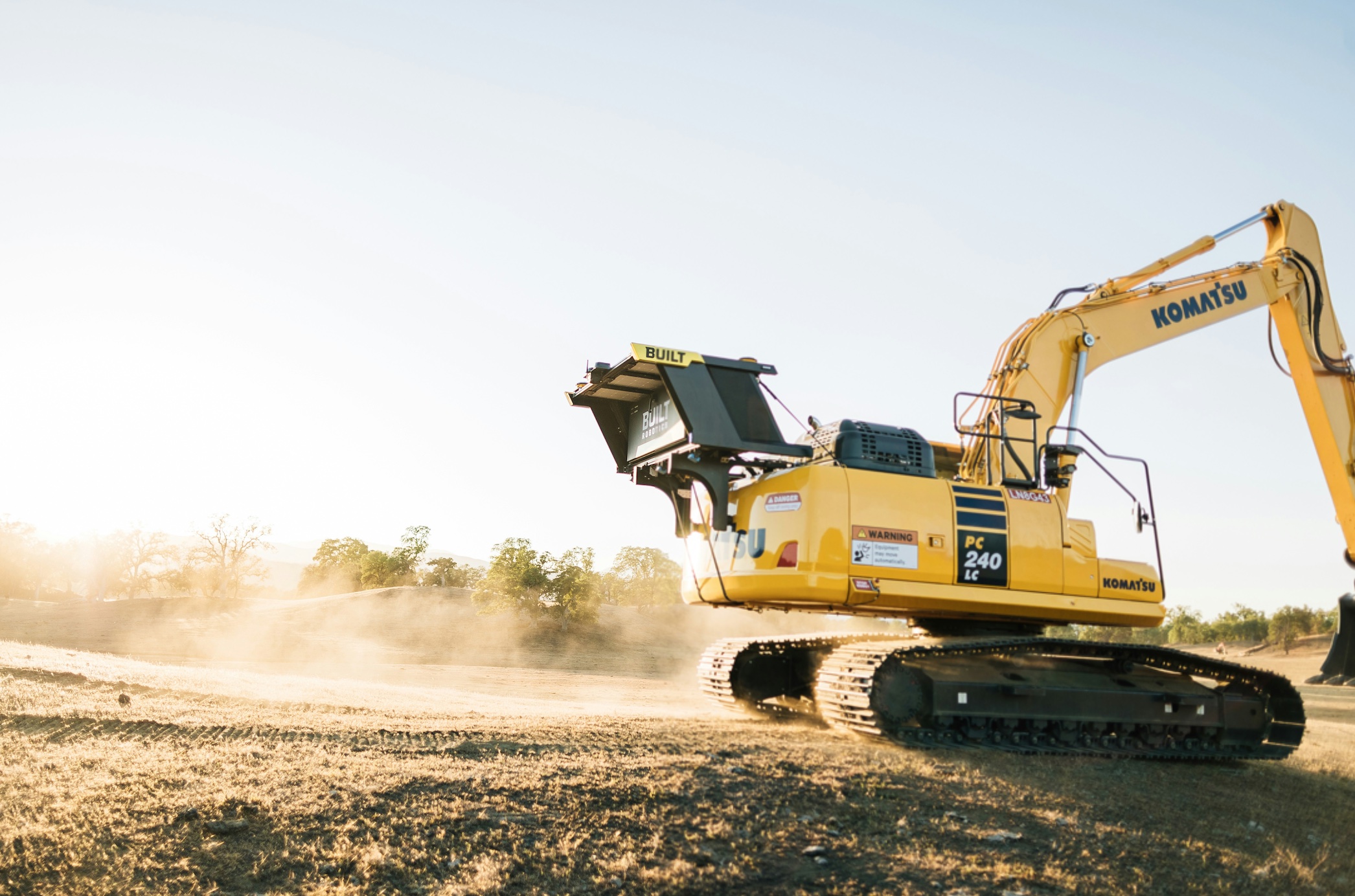 Yellow construction vehicle driving down dirt road; image by Built Robotics, via Unsplash.com.