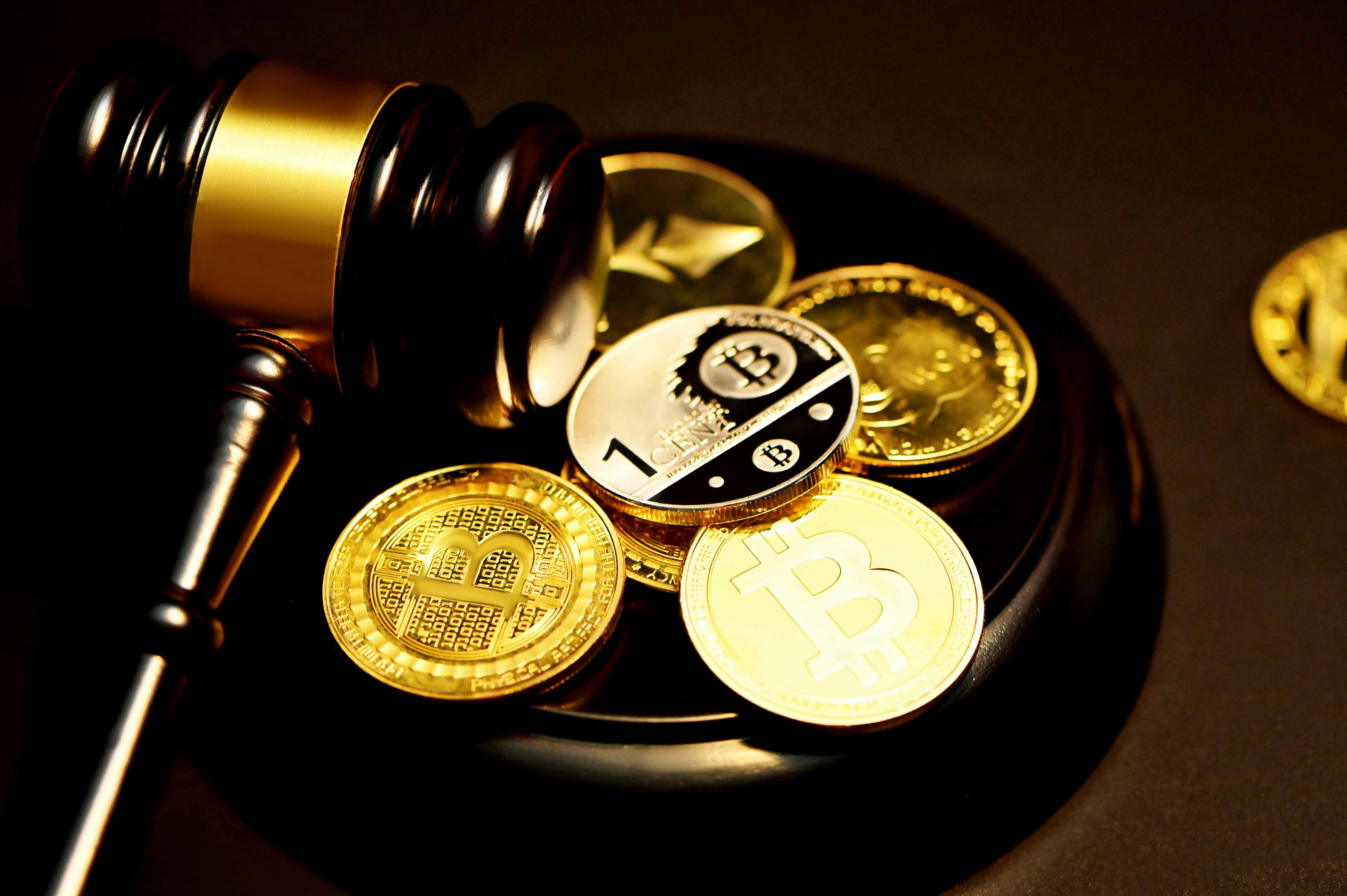 A pile of cryptocurrency next to a gavel; image by Kanchanara, via Unsplash.com.