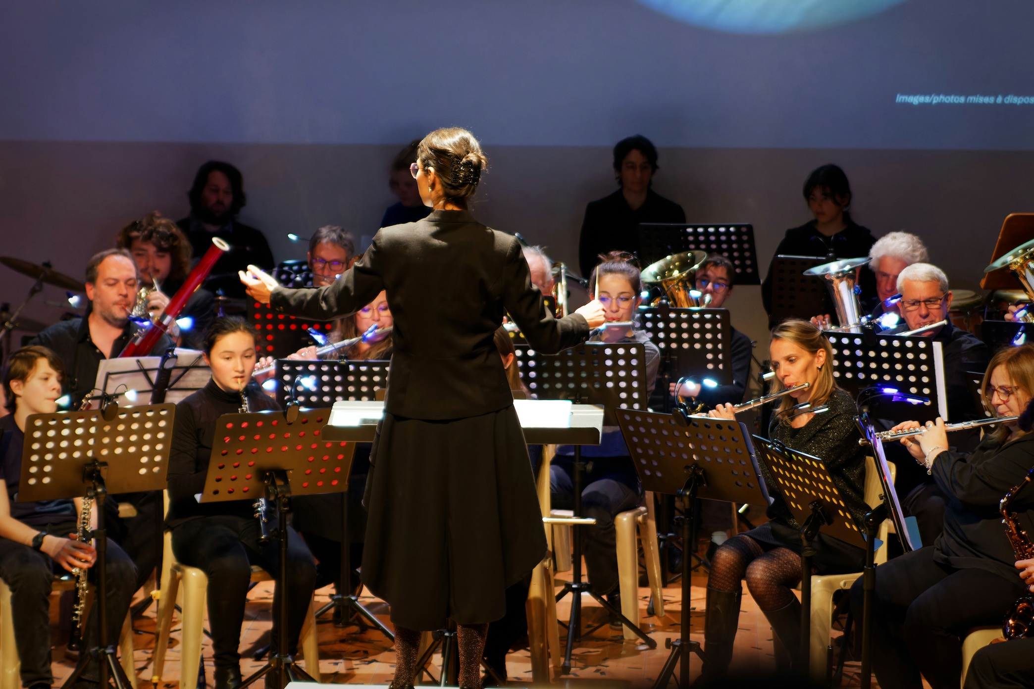 Conductor leads orchestra during a performance; image by Pierre Goiffon, via Unsplash.com.
