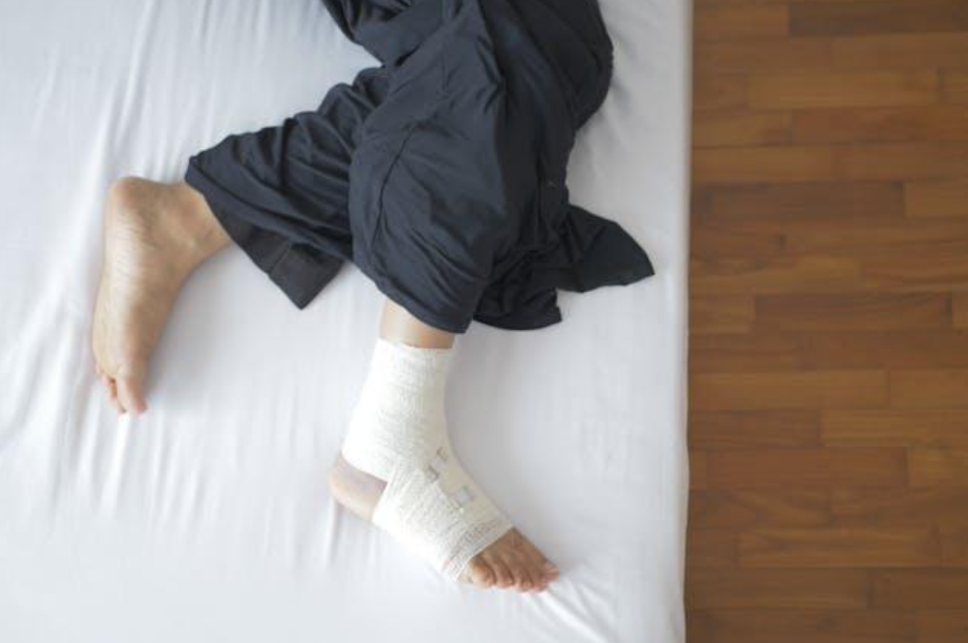Man in bed with bandage on foot; image by Towfiqu barbhuiya, via Pexels.com.