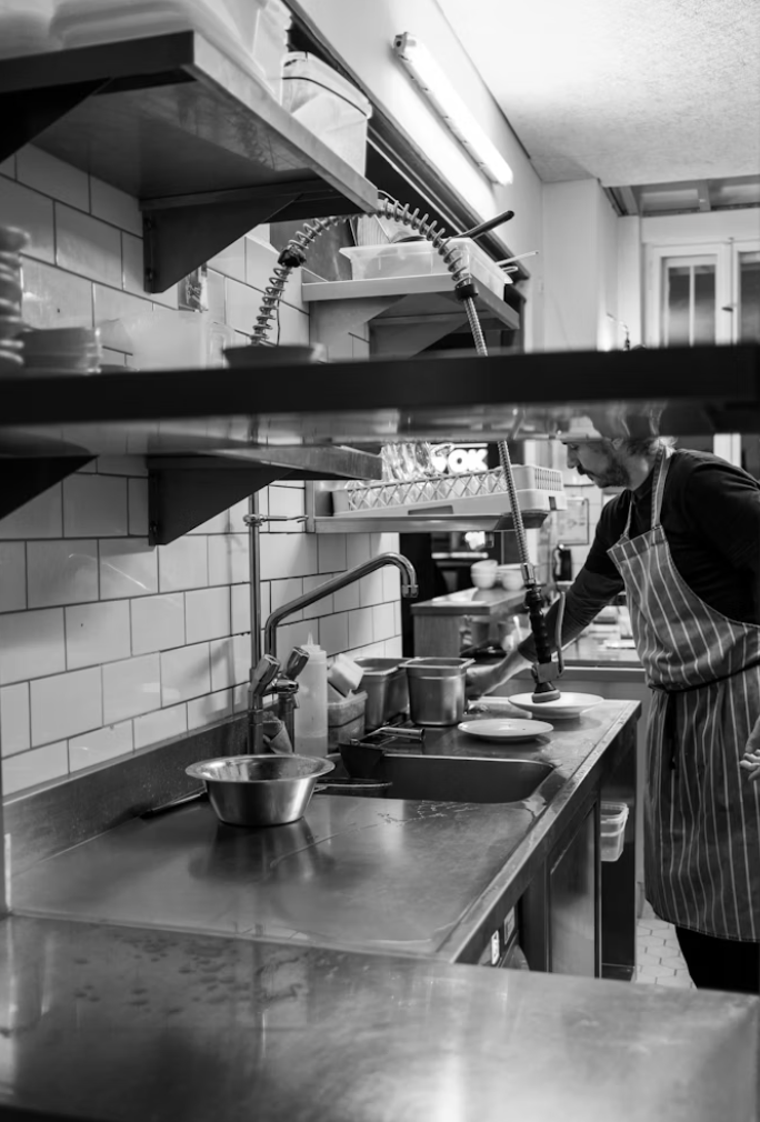Man in kitching preparing food by sink; image by Simon, via Unsplash.com.