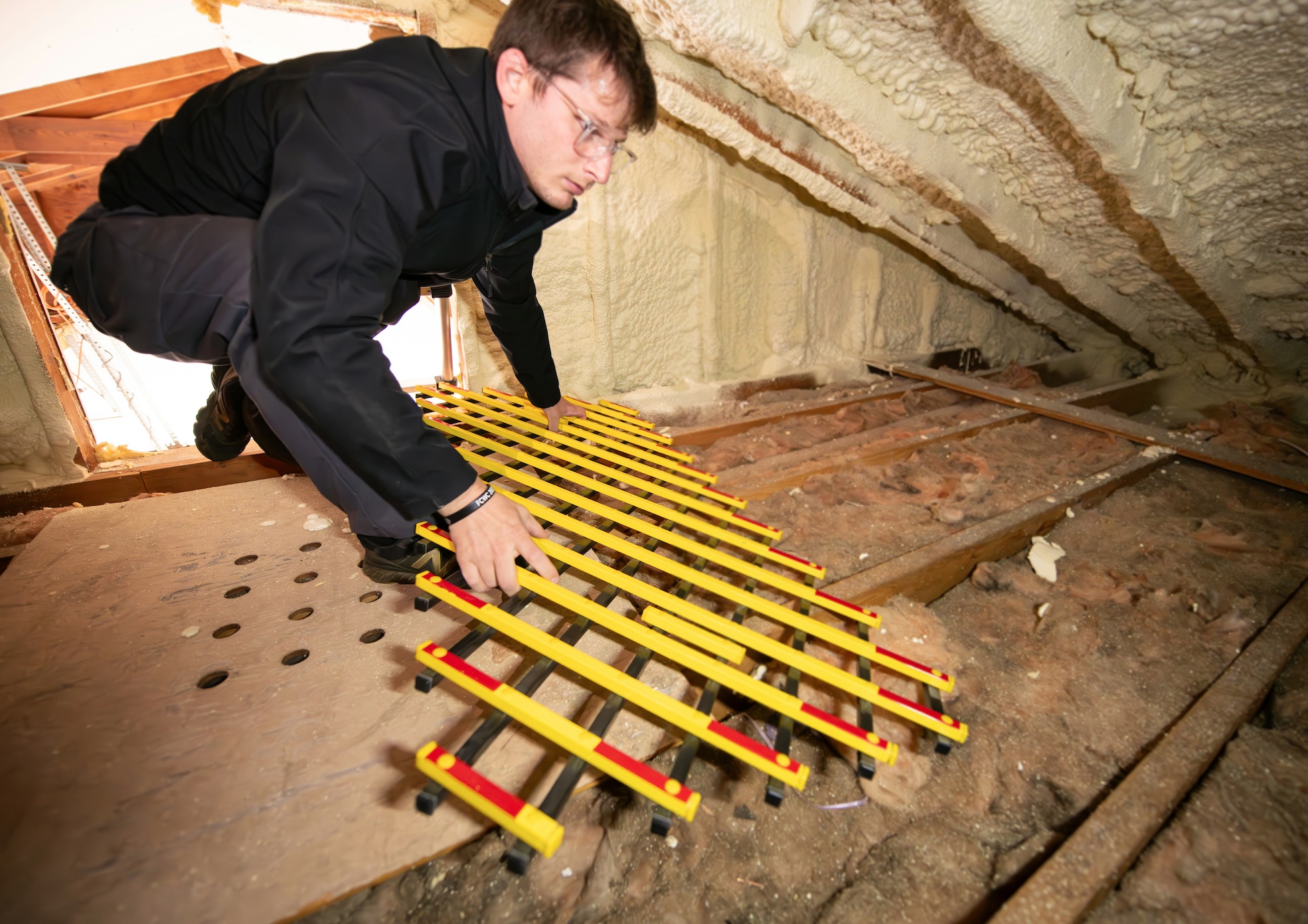 Man working on a floor in an attic; image by Marketing Department, via Unsplash.com.