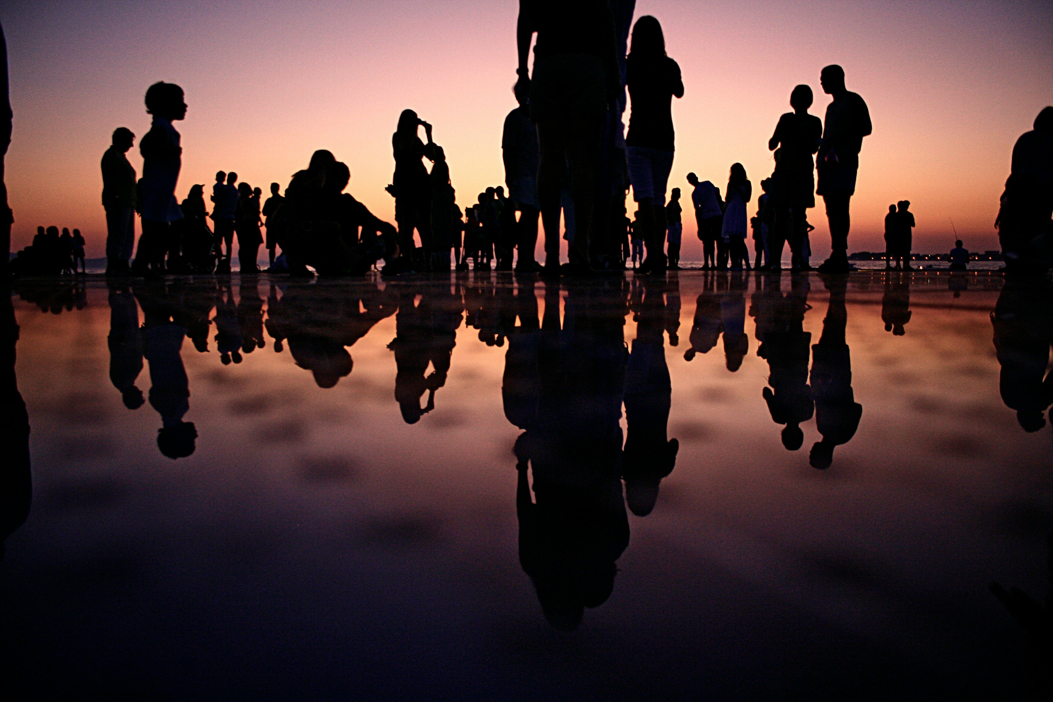 Silhouette of people standing on mirror during golden hour; image by. Mario Purisic, via Unsplash.com.