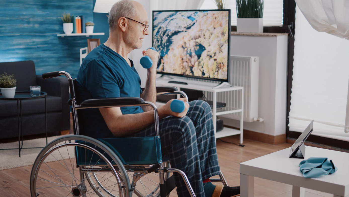 Pensioner sitting in wheelchair and doing exercises with dumbbells; image by DC Studio, via Magnific.com.