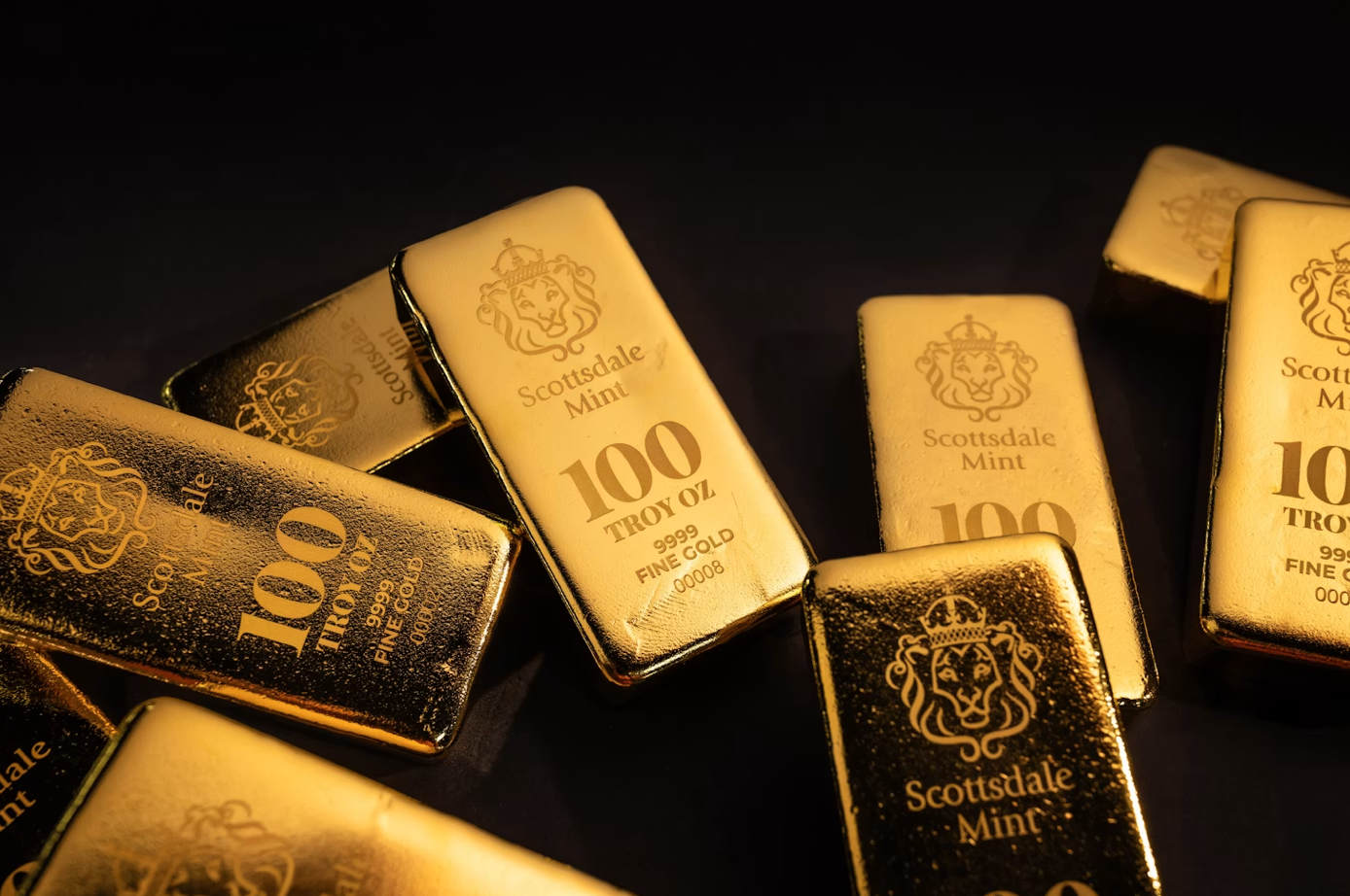 Several gold bars on a dark surface; image by Scottsdale Mint, via Unsplash.com.