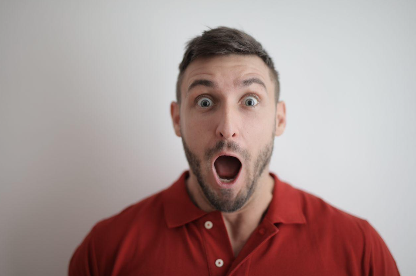 Surprised looking man in red button down shirt; image by Andrea Piacquadio, via Pexels.com.