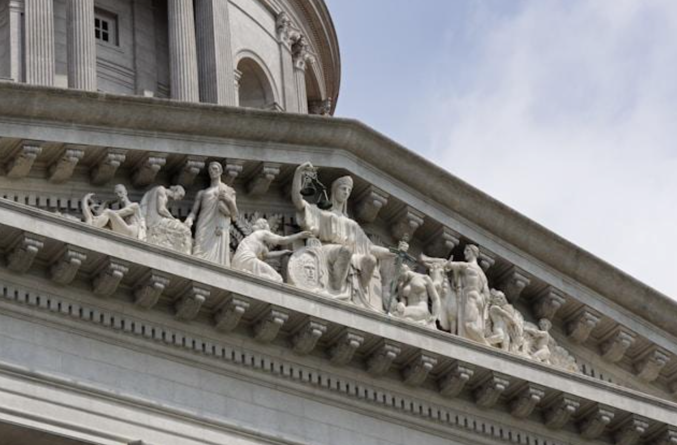 Closeup of building with statues on it; image by Sharon GM, via Unsplash.com.