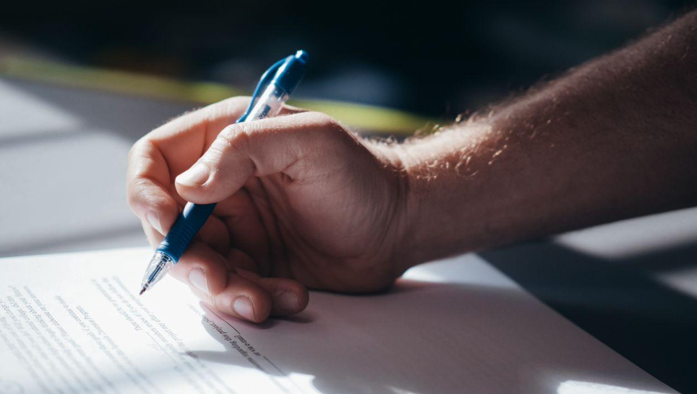 Man signing a document; image by Kindel Media, via Pexels.com.