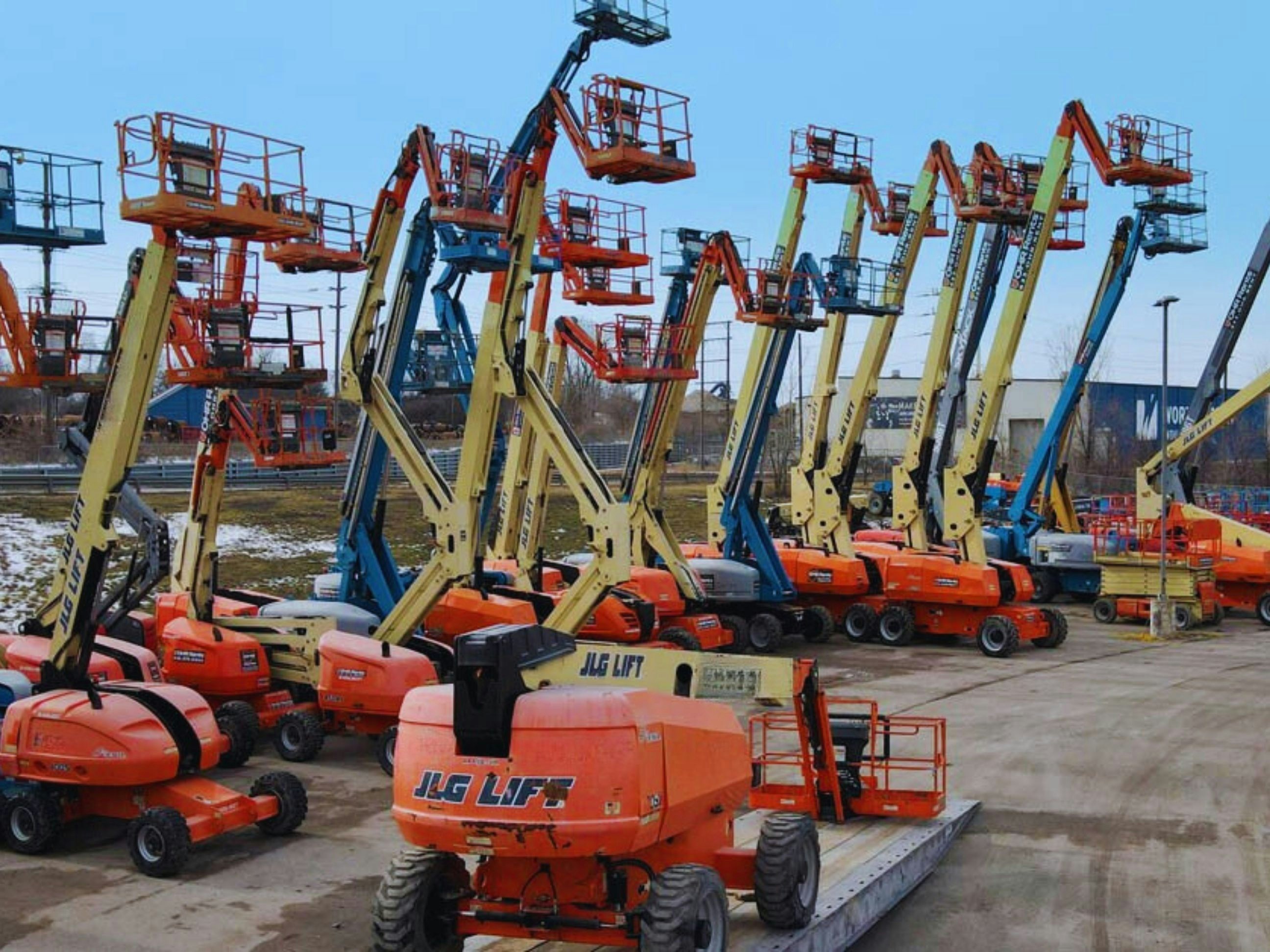 Multiple boom lifts parked in an outdoor lot; image by FleetNow, via Unsplash.com.