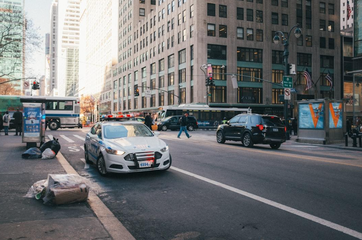 Police car on street next to building; image by Ethan Hansen, via Unsplash.com.