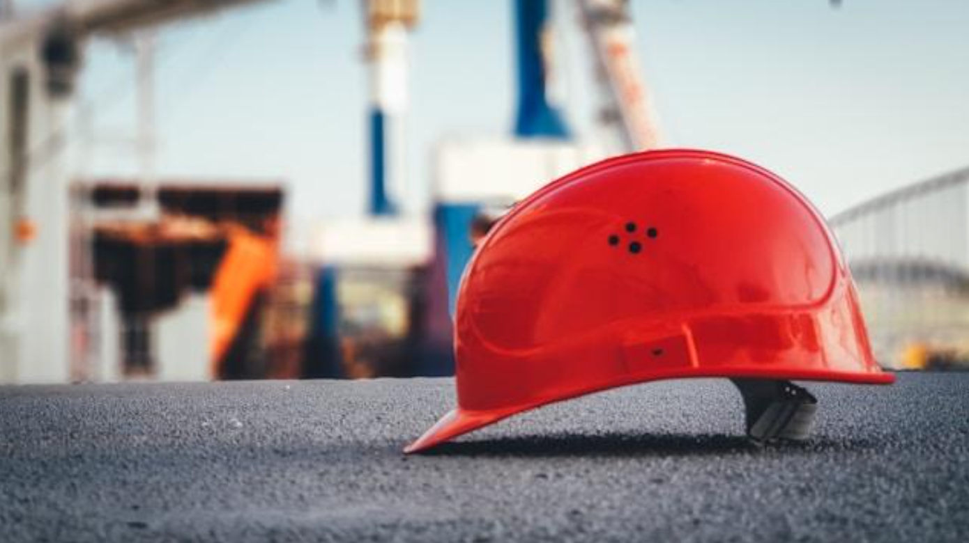 Red hard hat on pavement; image by Ũmit Yildirim, via Unsplash.com.