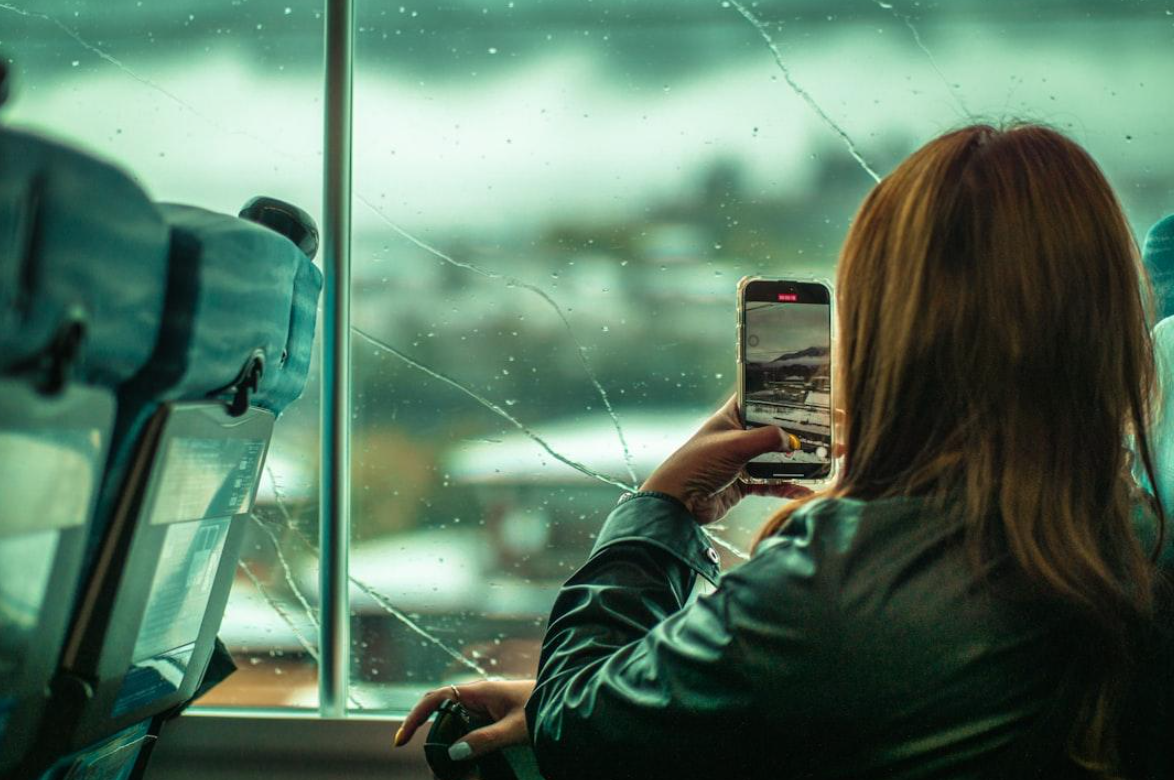 Woman taking a picture of a broken window; image by Alan W., via Unsplash.com.