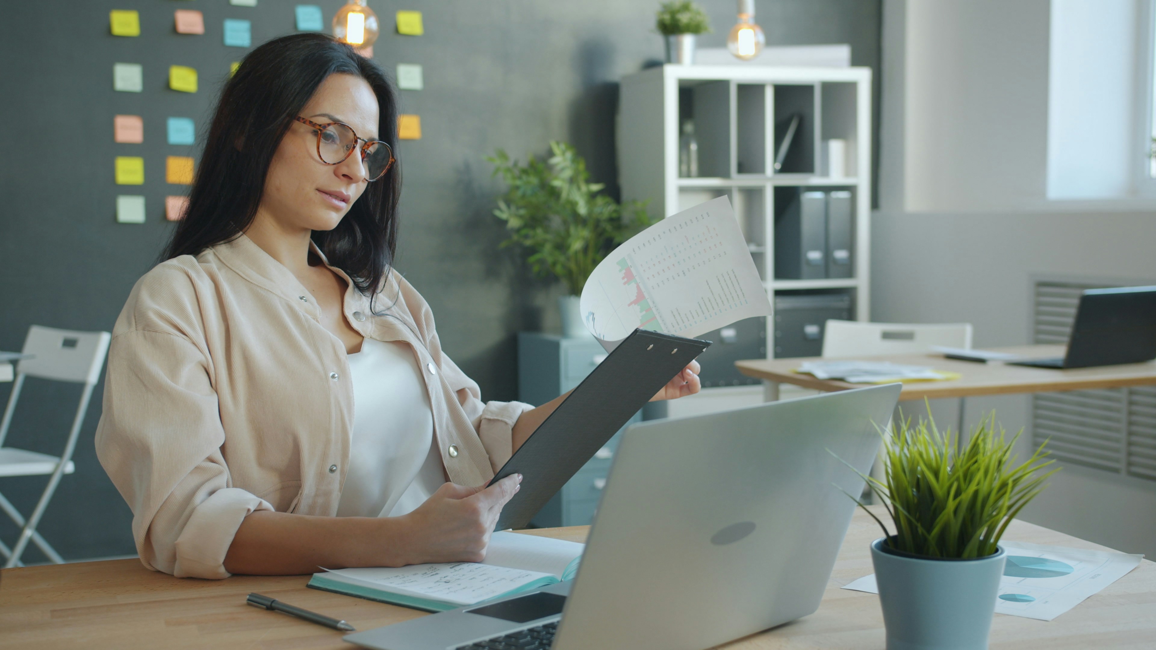 A small business owner reading a printed contract beside a laptop; image by Vitaly Gariev, via Unsplash.com.
