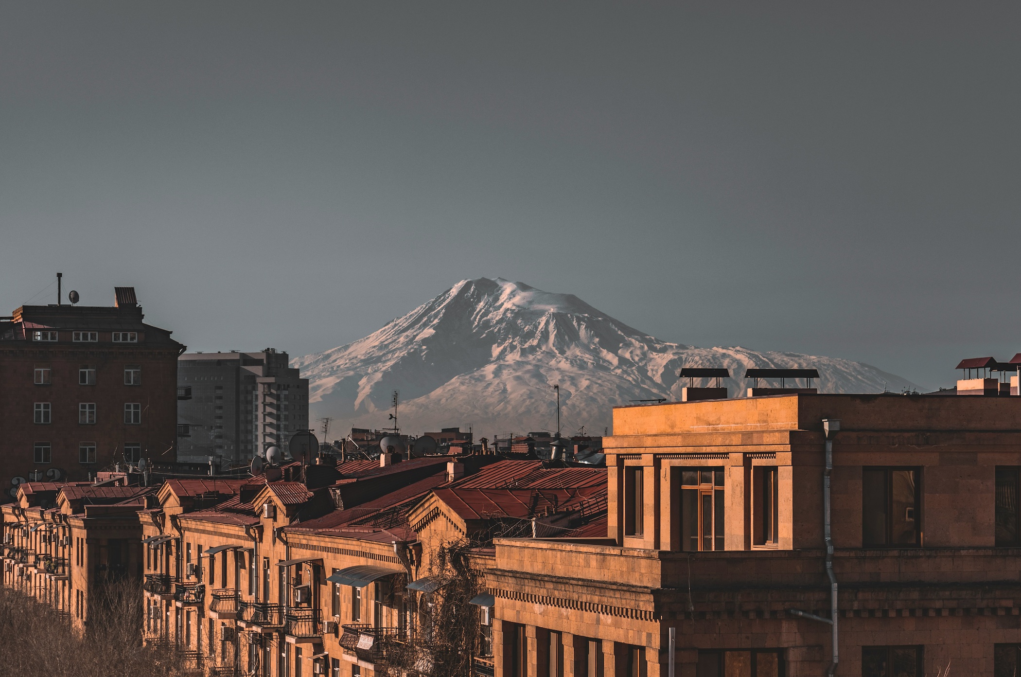 Brown concrete building near snow-covered mountain during daytime in Yerevan, Armenia; image by Gevorg Avetisyan, via Unsplash.com.