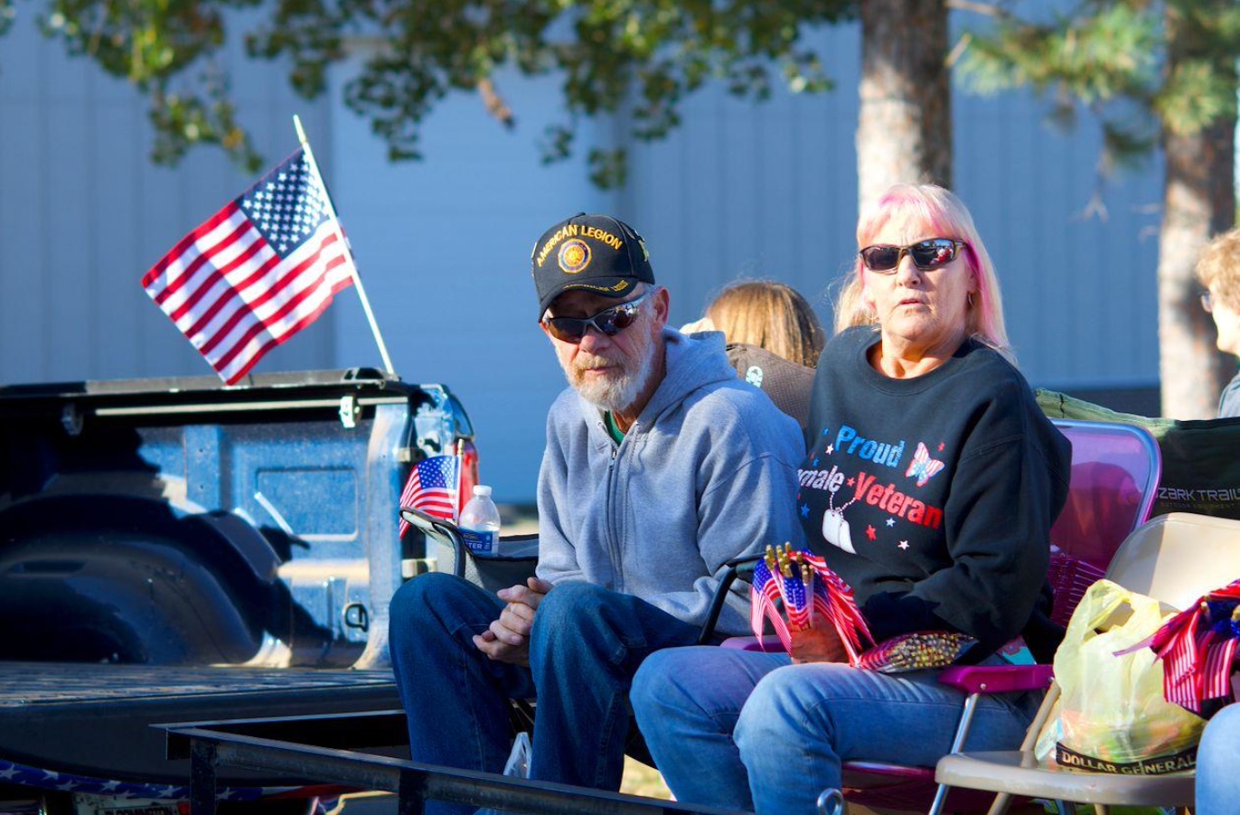 Proud veteran couple in patriotic parade setting; image by Charles Criscuolo, via Pexels.com.