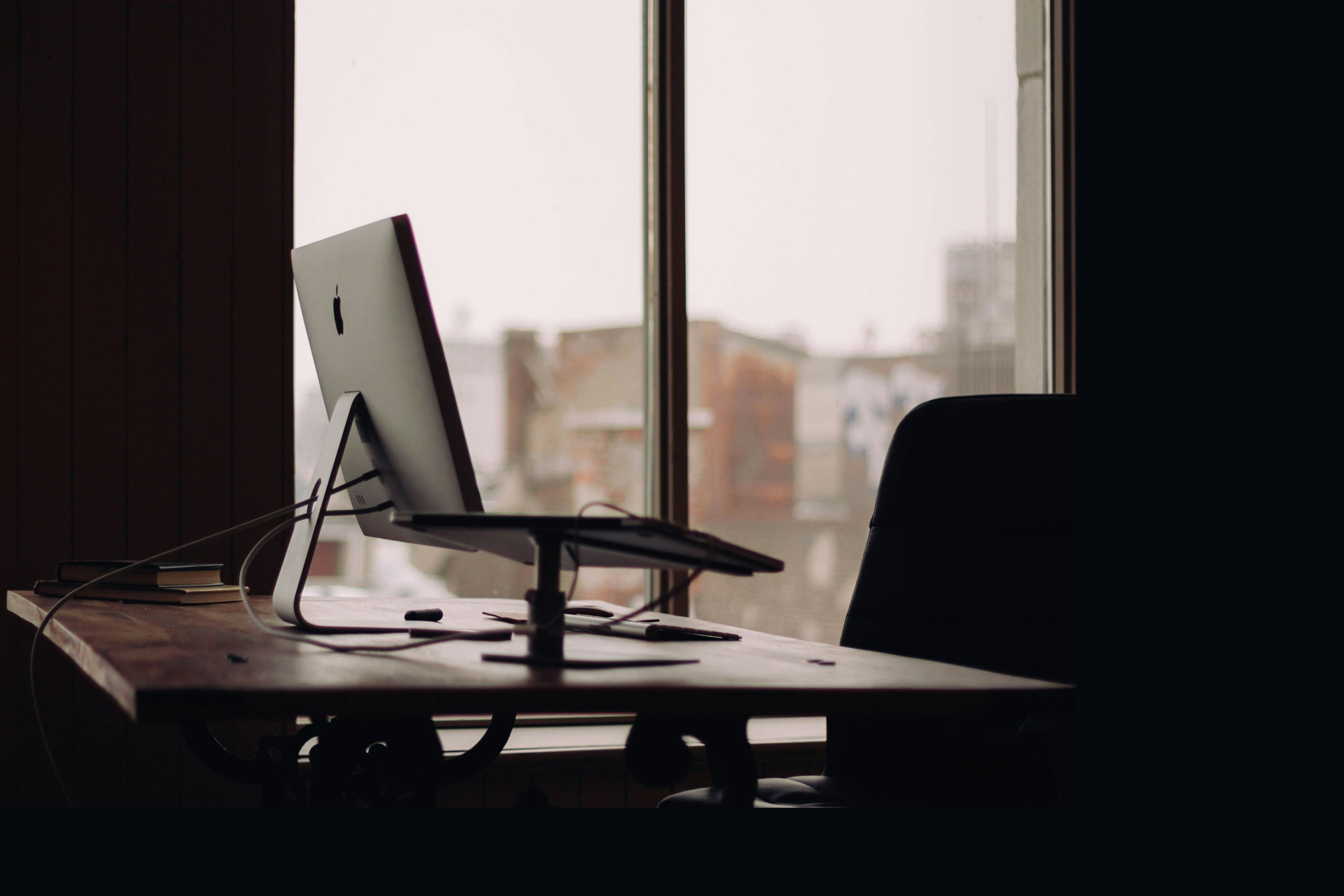 Silver iMac on desk inside empty office; image by Luke Chesser, via Unsplash.com.
